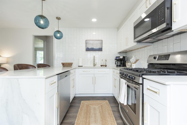 1621 E Madison St, South Bend, IN 46617 - kitchen with appliances with stainless steel finishes, a peninsula, decorative backsplash, dark wood-style floors, and white cabinetry