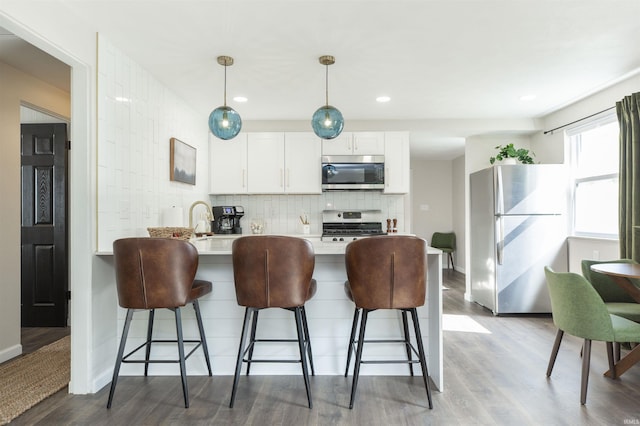 1621 E Madison St, South Bend, IN 46617 - kitchen with appliances with stainless steel finishes, light countertops, a breakfast bar, wood finished floors, and recessed lighting