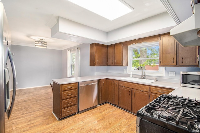 1822 Sherman Ave, South Bend, IN 46616 - kitchen featuring appliances with stainless steel finishes, ventilation hood, a peninsula, light wood-type flooring, and light countertops