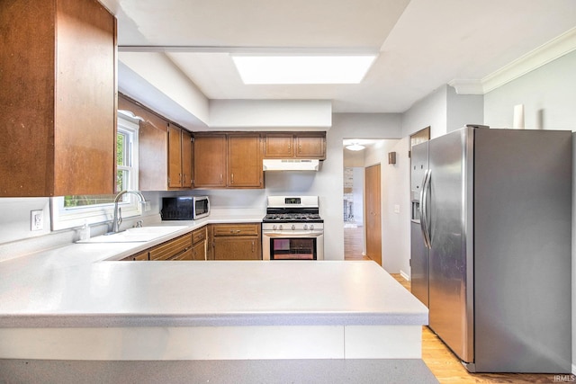 1822 Sherman Ave, South Bend, IN 46616 - kitchen with stainless steel appliances, under cabinet range hood, light countertops, a peninsula, and brown cabinets