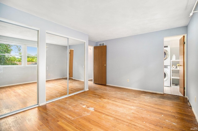 1822 Sherman Ave, South Bend, IN 46616 - unfurnished bedroom featuring stacked washer / drying machine, multiple closets, hardwood / wood-style floors, and ensuite bath