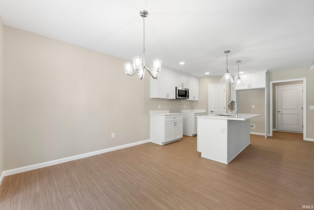 13969 Diavik Pl, Fort Wayne, IN 46845 - kitchen with stainless steel microwave, light wood finished floors, recessed lighting, white cabinets, and pendant lighting