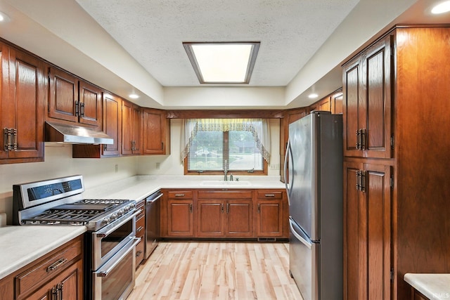 708 Forest Dr, Frankfort, IN 46041 - kitchen featuring appliances with stainless steel finishes, under cabinet range hood, light wood-style flooring, light countertops, and a textured ceiling