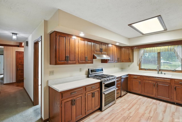 708 Forest Dr, Frankfort, IN 46041 - kitchen with stainless steel appliances, under cabinet range hood, a textured ceiling, light countertops, and brown cabinets
