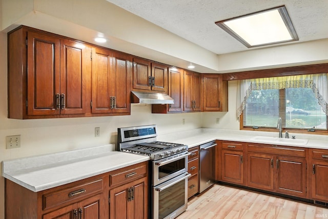 708 Forest Dr, Frankfort, IN 46041 - kitchen with appliances with stainless steel finishes, under cabinet range hood, light countertops, brown cabinets, and light wood finished floors