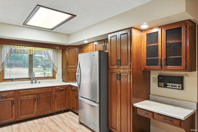 708 Forest Dr, Frankfort, IN 46041 - kitchen featuring freestanding refrigerator, brown cabinets, light countertops, glass insert cabinets, and light wood-type flooring