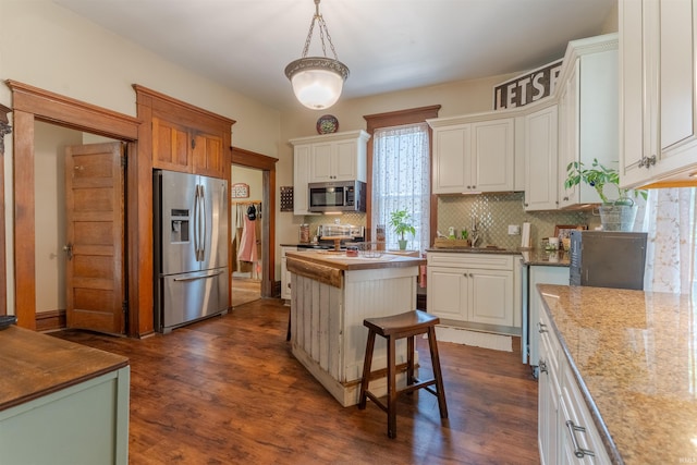 650 Main St, Rockport, IN 47635 - kitchen with stainless steel appliances, decorative backsplash, dark wood-style flooring, a kitchen island, and white cabinets