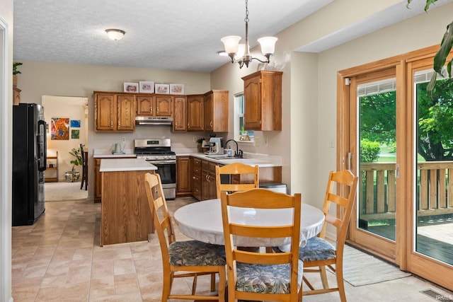 210 N Brookfield Dr, Lafayette, IN 47905 - kitchen with stainless steel range with gas stovetop, freestanding refrigerator, under cabinet range hood, a center island, and brown cabinetry
