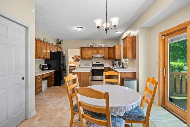 210 N Brookfield Dr, Lafayette, IN 47905 - kitchen featuring stainless steel gas range oven, black fridge, under cabinet range hood, brown cabinetry, and a chandelier