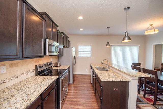 1860 Sandpiper Dr, West Lafayette, IN 47906 - kitchen featuring stainless steel appliances, wood finished floors, a kitchen island with sink, dark brown cabinets, and backsplash