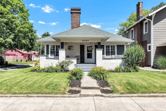 4721 Carrollton Ave, Indianapolis, IN 46205 - bungalow with a front yard, covered porch, a chimney, and a shingled roof