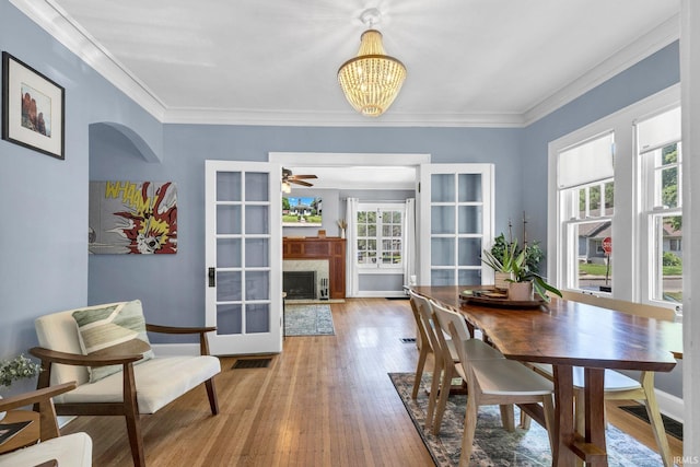 4721 Carrollton Ave, Indianapolis, IN 46205 - dining space featuring a chandelier, wood finished floors, a fireplace, crown molding, and a ceiling fan