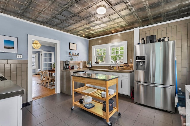 4721 Carrollton Ave, Indianapolis, IN 46205 - kitchen featuring stainless steel refrigerator with ice dispenser, white cabinets, an ornate ceiling, dark tile patterned flooring, and ornamental molding