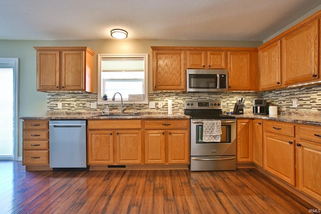 3517 Boulder Pass, Fort Wayne, IN 46818 - kitchen featuring appliances with stainless steel finishes, decorative backsplash, dark wood-style flooring, and dark stone countertops