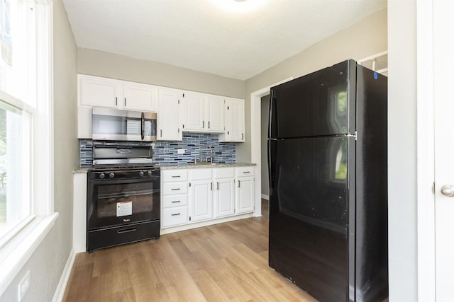 717 S Falcon St, South Bend, IN 46619 - kitchen with black appliances, white cabinetry, light wood-style floors, and decorative backsplash