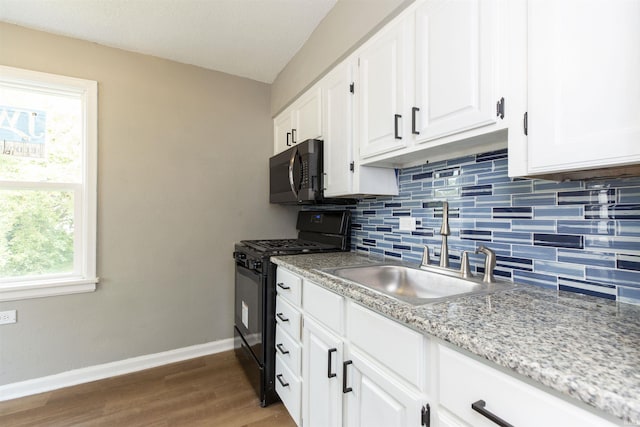 717 S Falcon St, South Bend, IN 46619 - kitchen with black gas stove, wood finished floors, tasteful backsplash, white cabinets, and light stone countertops
