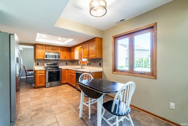 11215 Crested Oak Ct, Fort Wayne, IN 46845 - kitchen featuring appliances with stainless steel finishes, decorative backsplash, light countertops, and brown cabinets