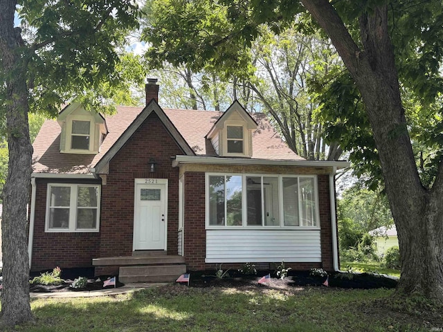 2521 N Red Bank Rd, Evansville, IN 47720 - view of front of house featuring a chimney, brick siding, and a sunroom