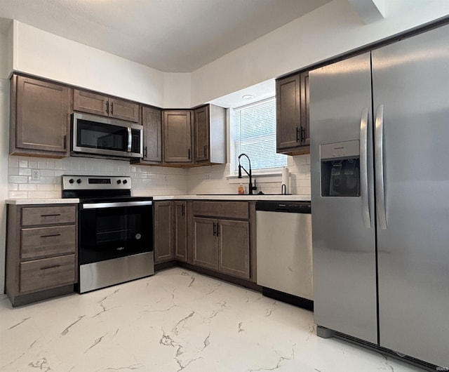 2521 N Red Bank Rd, Evansville, IN 47720 - kitchen featuring appliances with stainless steel finishes, dark brown cabinetry, light marble finish floors, light countertops, and tasteful backsplash