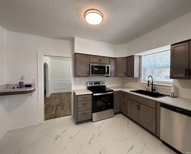 2521 N Red Bank Rd, Evansville, IN 47720 - kitchen with stainless steel appliances, dark brown cabinetry, backsplash, light countertops, and a textured ceiling