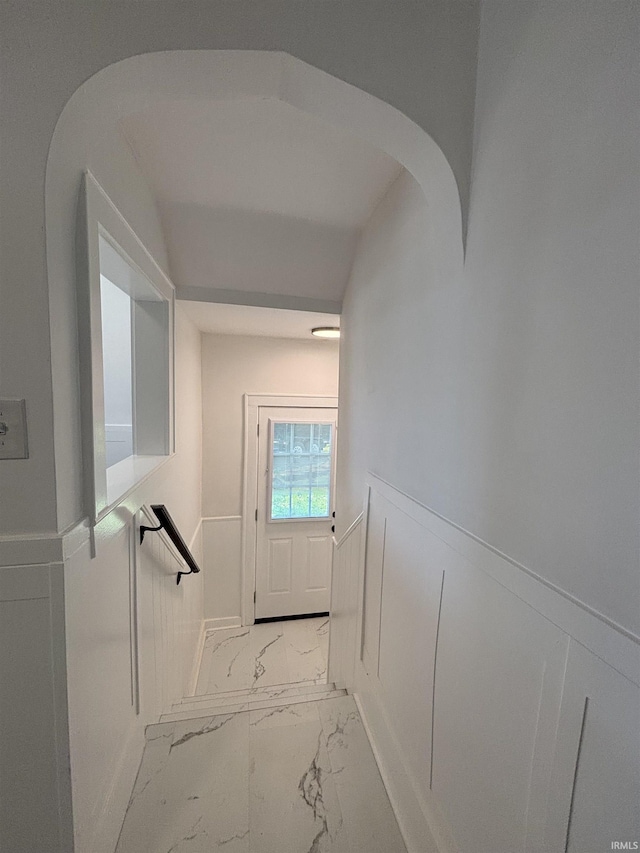 2521 N Red Bank Rd, Evansville, IN 47720 - hallway with marble look tiles, a wainscoted wall, and arched walkways