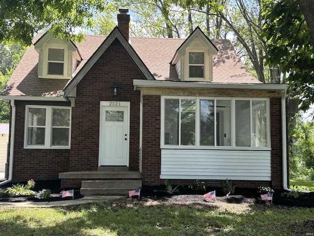 2521 N Red Bank Rd, Evansville, IN 47720 - view of front facade with a chimney, brick siding, and a sunroom
