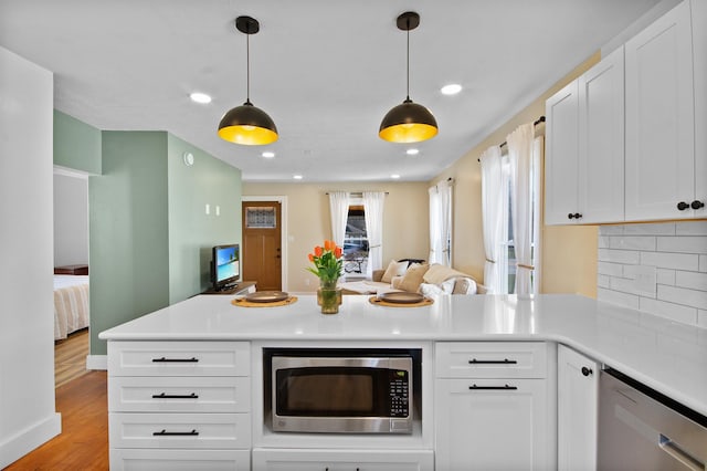 54054 N Ironwood Rd, South Bend, IN 46635 - kitchen with appliances with stainless steel finishes, open floor plan, a peninsula, tasteful backsplash, and light countertops