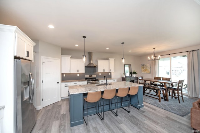 5358 Maize Dr, West Lafayette, IN 47906 - kitchen with appliances with stainless steel finishes, wall chimney exhaust hood, light wood-type flooring, white cabinetry, and a kitchen island with sink