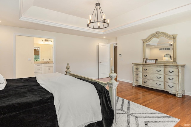 8196 E Walnut Rdg, New Carlisle, IN 46552 - bedroom featuring a tray ceiling, wood finished floors, a chandelier, ensuite bathroom, and crown molding