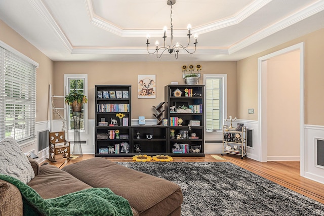 8196 E Walnut Rdg, New Carlisle, IN 46552 - living room featuring ornamental molding, a chandelier, wood finished floors, a raised ceiling, and a wainscoted wall