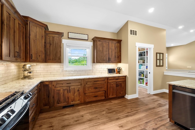7316 Butt Rd, Fort Wayne, IN 46818 - kitchen with stainless steel dishwasher, backsplash, gas range, light stone countertops, and wood finished floors
