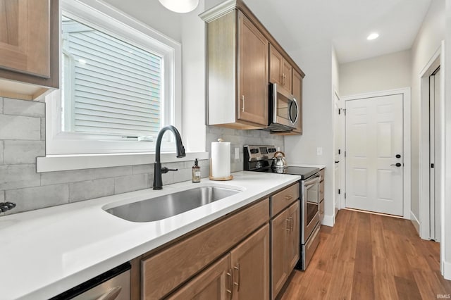 1381 Codorna Cv, Fort Wayne, IN 46804 - kitchen with stainless steel appliances, backsplash, light wood finished floors, light countertops, and brown cabinetry