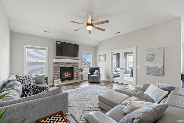 936 Switchfoot Dr, Huntertown, IN 46748 - living area featuring a ceiling fan, wood finished floors, vaulted ceiling, a stone fireplace, and french doors