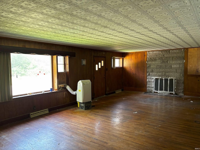 11592 E Main St, Owensburg, IN 47453 - unfurnished living room featuring plenty of natural light, wood walls, a stone fireplace, wood finished floors, and an ornate ceiling