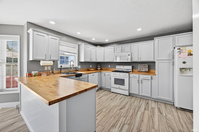 4310 Ashard Dr, South Bend, IN 46628 - kitchen with white appliances, butcher block counters, light wood-style floors, a peninsula, and recessed lighting