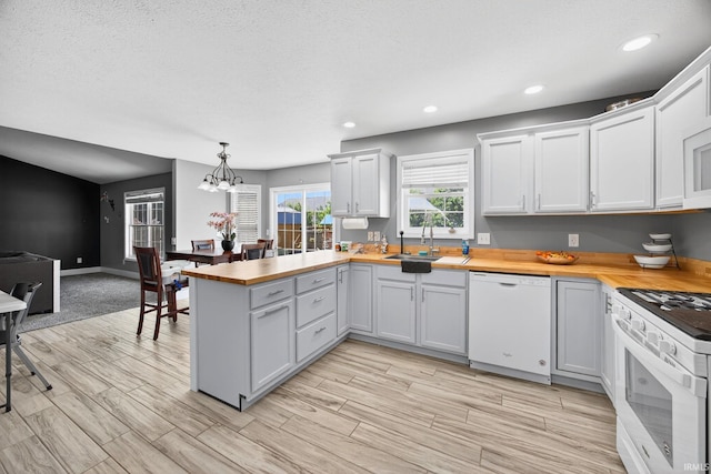 4310 Ashard Dr, South Bend, IN 46628 - kitchen with white appliances, wooden counters, a peninsula, a chandelier, and recessed lighting