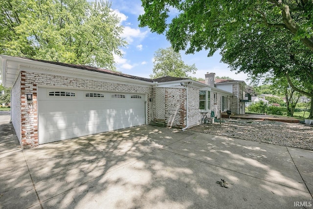 3111 N Eastlake Dr, Elkhart, IN 46514 - view of side of property featuring a chimney, concrete driveway, an attached garage, and brick siding