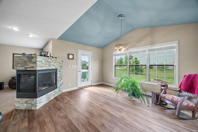 378 Buchanan St, West Lafayette, IN 47906 - living area with lofted ceiling, wood finished floors, a stone fireplace, and a chandelier