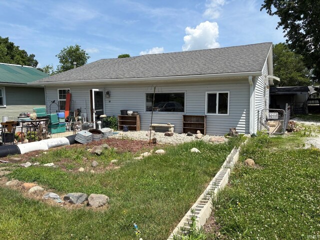 back of house featuring a yard and a shingled roof