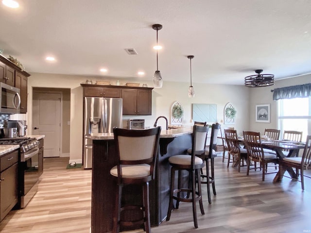 3065 E Butler Ct, Columbia City, IN 46725 - kitchen with stainless steel appliances, light wood finished floors, dark brown cabinets, recessed lighting, and a breakfast bar area