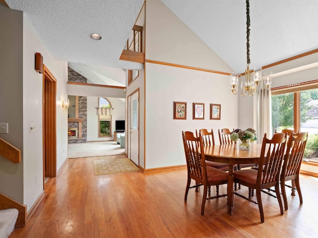 1031 Skyline Pass, Fort Wayne, IN 46825 - dining room featuring vaulted ceiling, a textured ceiling, light wood finished floors, a chandelier, and a fireplace