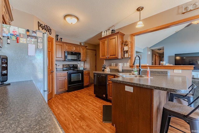 12 Chrysler Ave, Wabash, IN 46992 - kitchen with black appliances, a breakfast bar, dark countertops, a peninsula, and light wood-style flooring