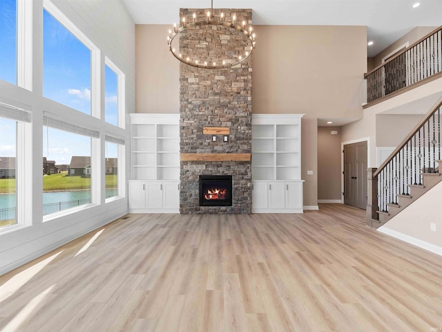 13092 Hallux Cv, Fort Wayne, IN 46845 - unfurnished living room featuring a high ceiling, wood finished floors, stairway, a fireplace, and a water view