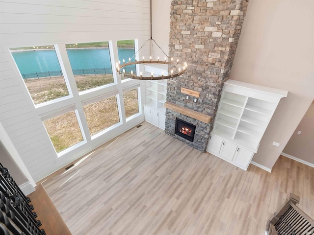 13092 Hallux Cv, Fort Wayne, IN 46845 - unfurnished living room featuring wood finished floors, a chandelier, a stone fireplace, a water view, and a towering ceiling