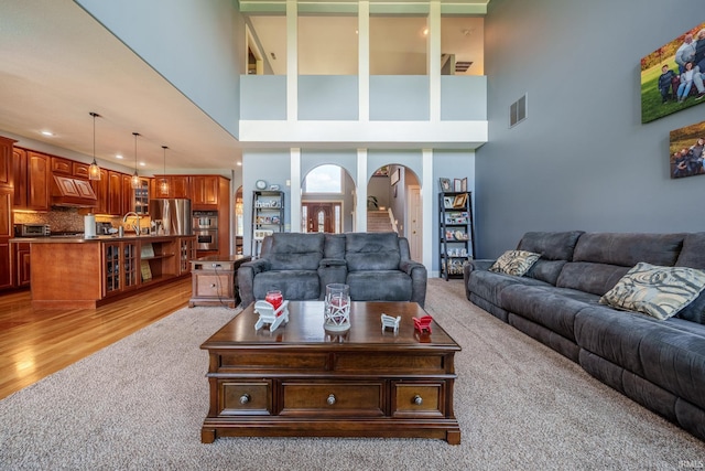 2220 Meadowbrook Dr, Marion, IN 46952 - living room with arched walkways, light colored carpet, a high ceiling, recessed lighting, and light wood finished floors