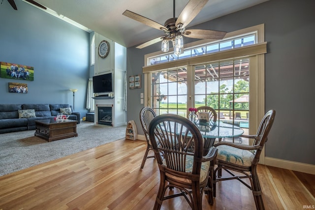 2220 Meadowbrook Dr, Marion, IN 46952 - dining room featuring ceiling fan, a towering ceiling, light wood-style floors, and a glass covered fireplace