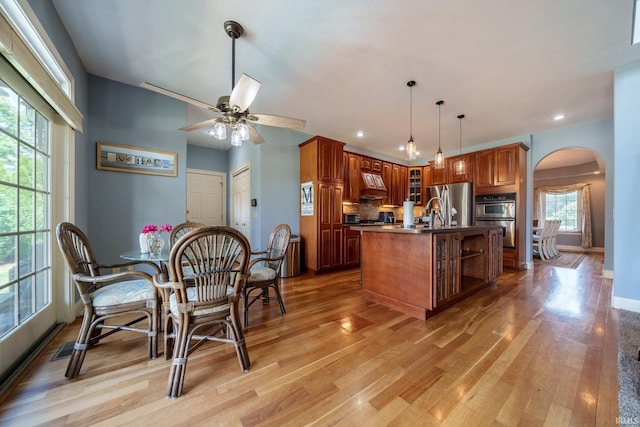2220 Meadowbrook Dr, Marion, IN 46952 - kitchen with arched walkways, glass insert cabinets, stainless steel appliances, light wood-style flooring, and ceiling fan