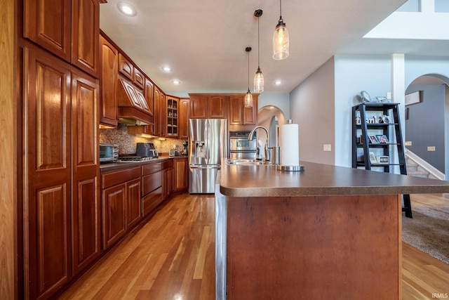 2220 Meadowbrook Dr, Marion, IN 46952 - kitchen featuring stainless steel appliances, arched walkways, dark countertops, light wood-style flooring, and custom exhaust hood