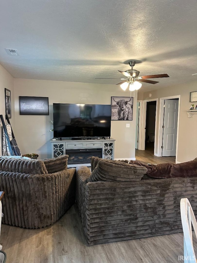 148 SW 8th St, Linton, IN 47441 - living room featuring wood finished floors, a ceiling fan, a textured ceiling, and a fireplace