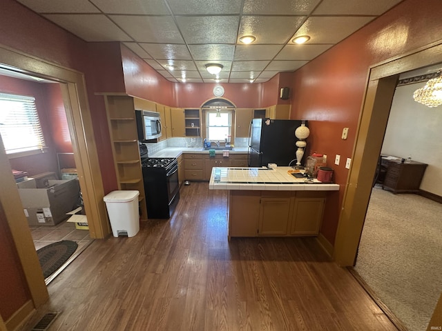 448 N 7th St, Mitchell, IN 47446 - kitchen with black gas range oven, freestanding refrigerator, tile countertops, stainless steel microwave, and a peninsula